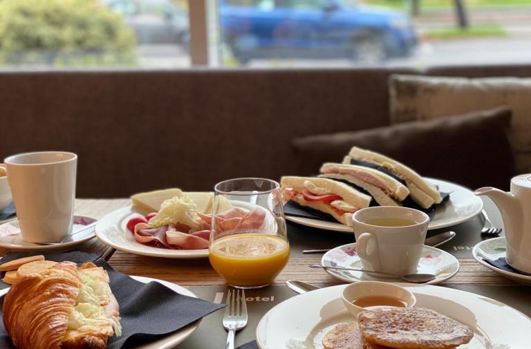 Colazione con croissant, sandwich, pancake, succo d'arancia e tè.