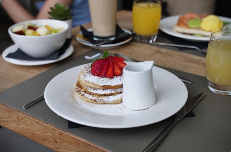 Pancake con fragole e zucchero a velo, succo d'arancia e macedonia.