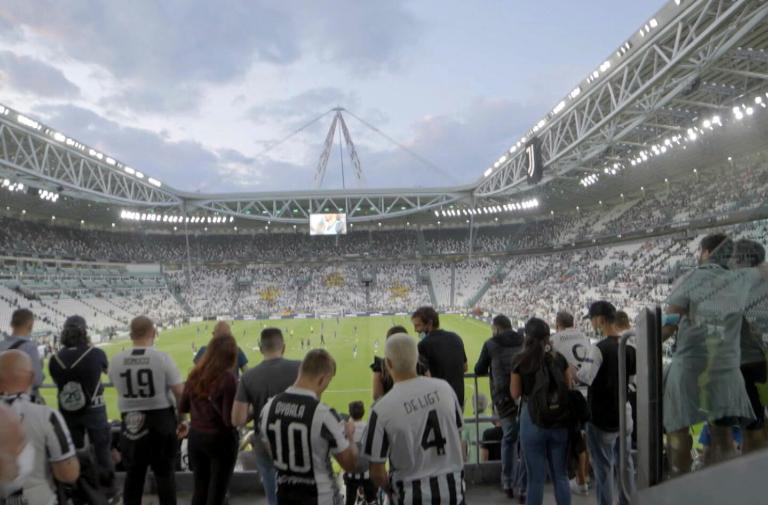 Stadio affollato con tifosi durante una partita di calcio serale.