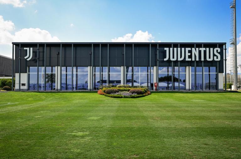 Edificio moderno con logo Juventus su prato verde.