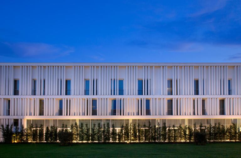 Edificio moderno con facciata bianca e illuminazione notturna.