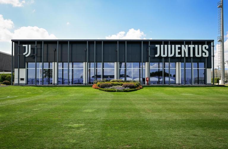 Modern Juventus building, green lawn, blue sky, sporty and prestigious atmosphere.